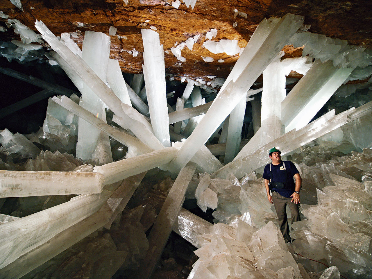 Awe-inspiring giant gypsum crystals in Mexico's Cave of Crystals dwarf a human figure, showcasing their immense size.