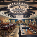 Rustic dining area with wood beams and oversized light fixtures at Mexican Sugar, creating a warm and inviting atmosphere.