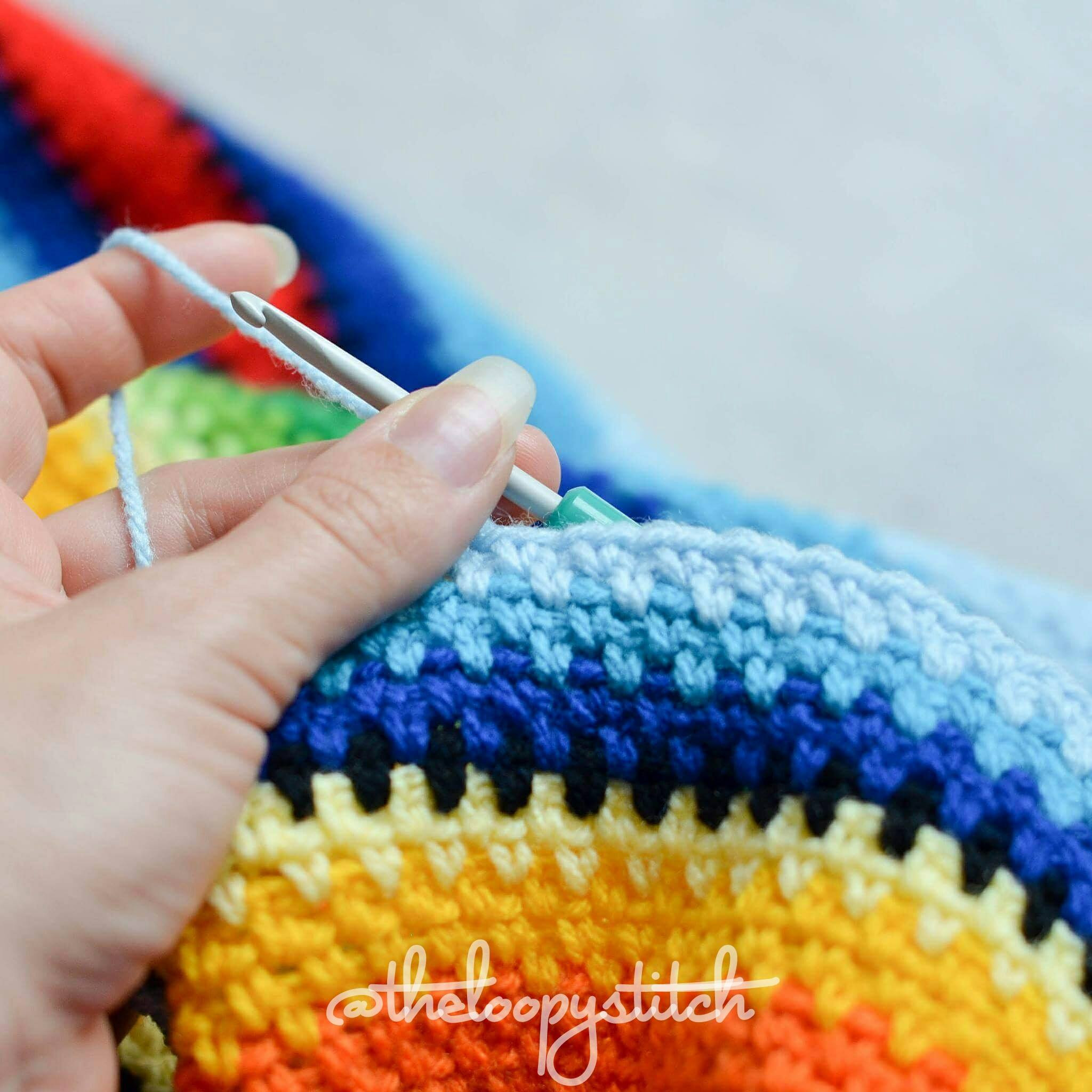 Folded crochet Mexican blanket displaying the colorful stripes