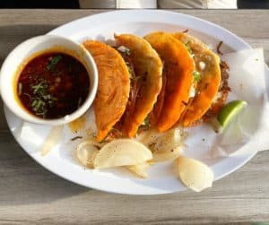 A close-up shot of quesabirria tacos with a side of red salsa from Jose's Tacos in Detroit.