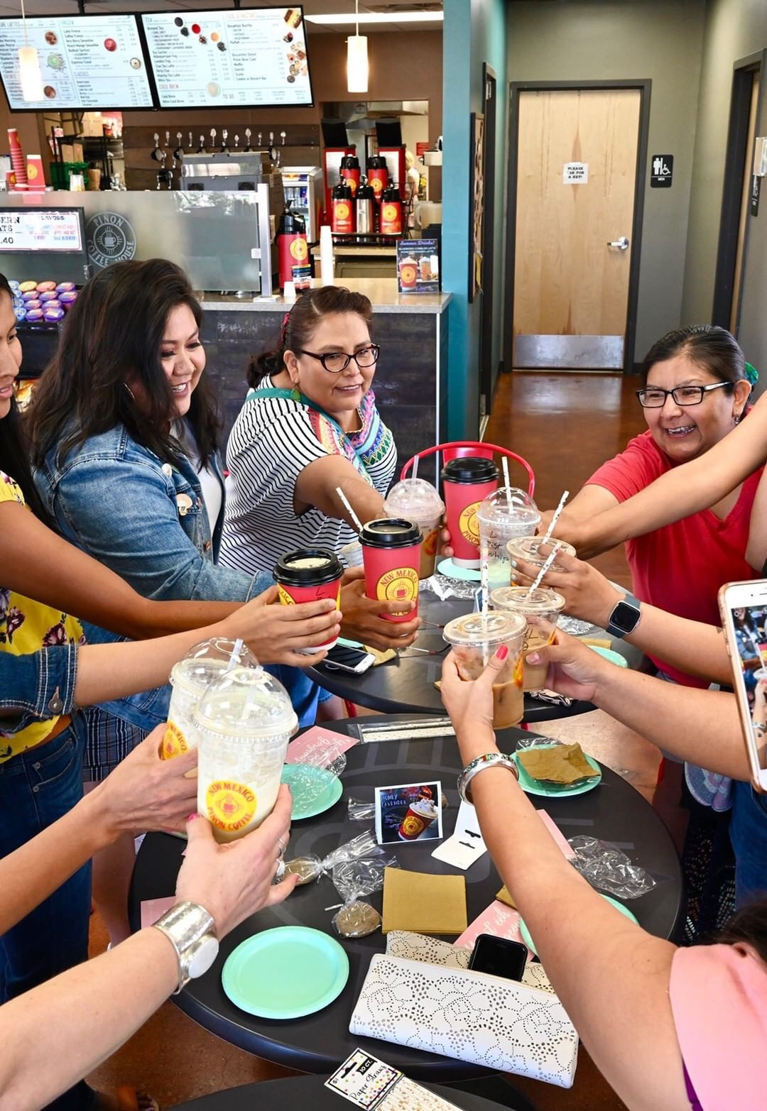 A close up of hands raising coffee cups in a toast, symbolizing the community spirit of the event.
