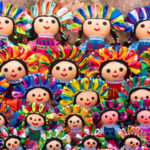 A close-up of a Lelé doll's face, showcasing its embroidered smile and colorful ribbons