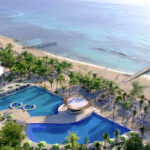 alt= Aerial view of The Fives Beach Hotel & Residences with its beachfront location and swimming pools.