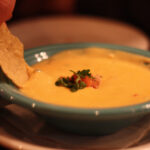 Close-up shot of Iguana Mexican Grill's Seven Pepper Queso, showcasing its cheesy and gooey texture, perfect as a flavorful appetizer.