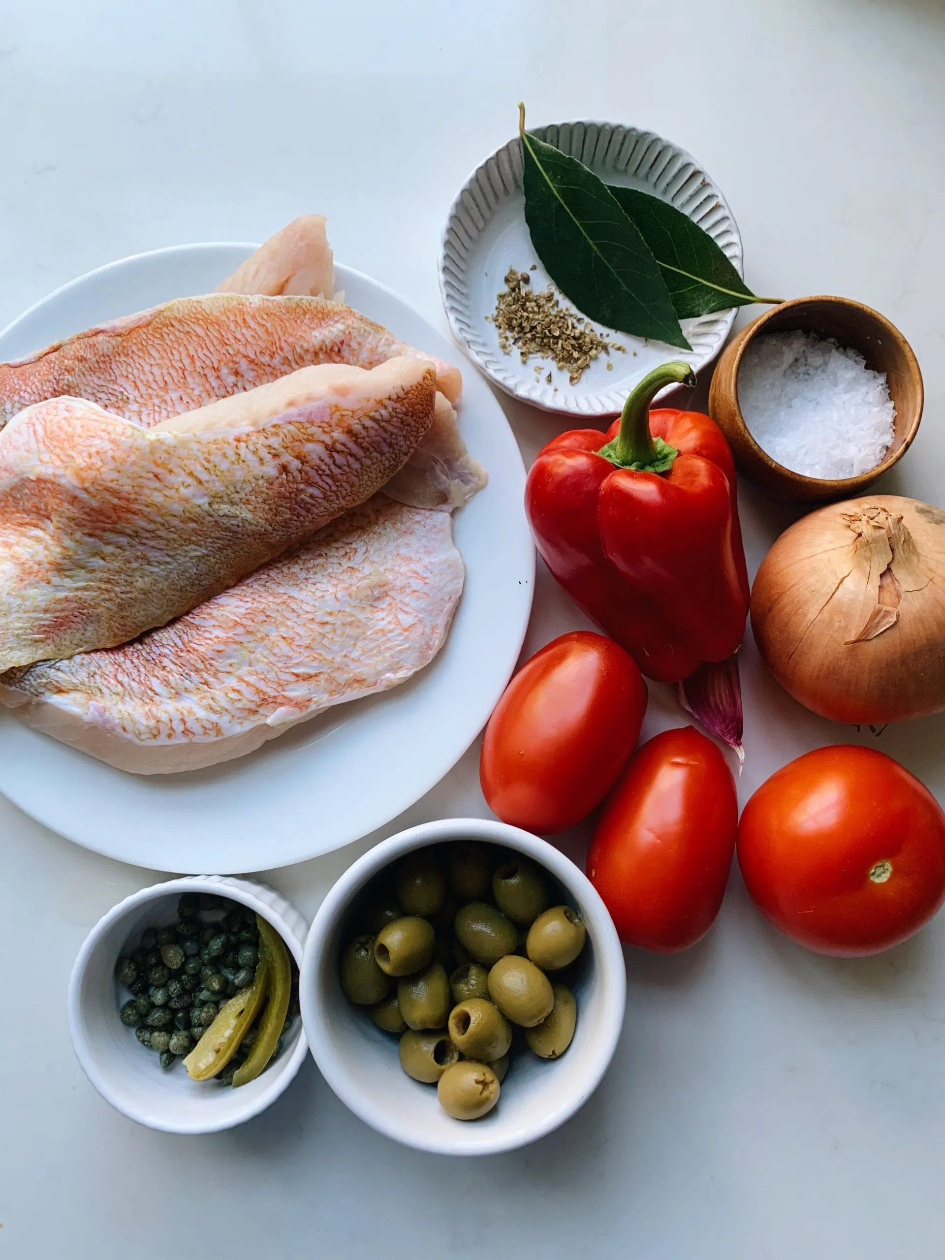 Close-up shot of Pescado a la Veracruzana, highlighting the texture of the flaky fish and the vibrant colors of the sauce ingredients like tomatoes, olives, and peppers. Steam gently rises from the dish, indicating its warmth and freshness.