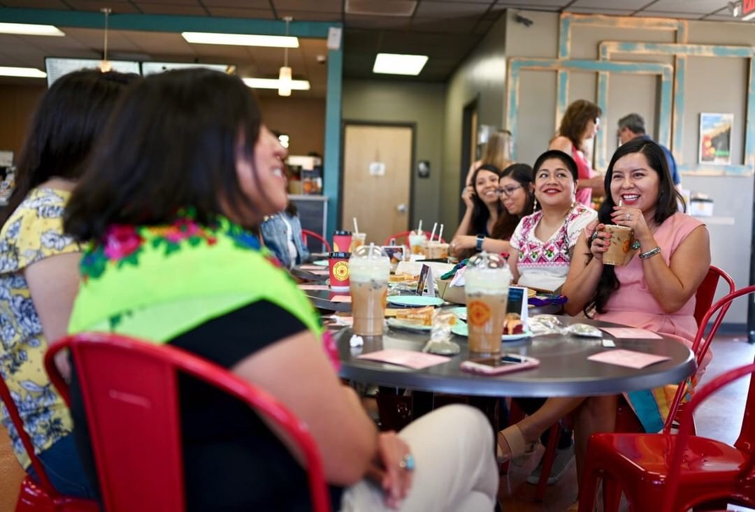 Attendees clinking coffee cups together in a Piñon Coffee cheers, celebrating the shared experience.