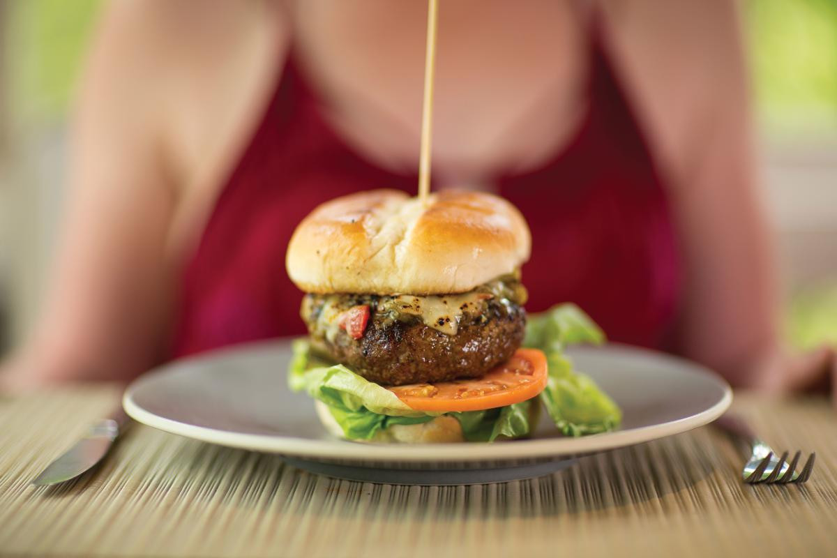 A close-up shot of a green chile cheeseburger from the Blue Heron Restaurant at the New Mexico resort, showcasing the juicy patty, melted cheese, and green chiles.