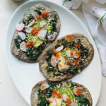 Close-up shot of a spinach huarache topped with fresh ingredients, showcasing the texture of the masa and the vibrant colors of the toppings.