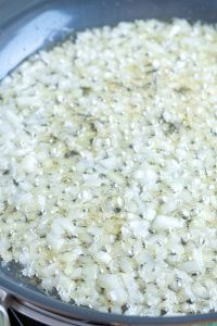 Sautéing minced onions in lard in a skillet