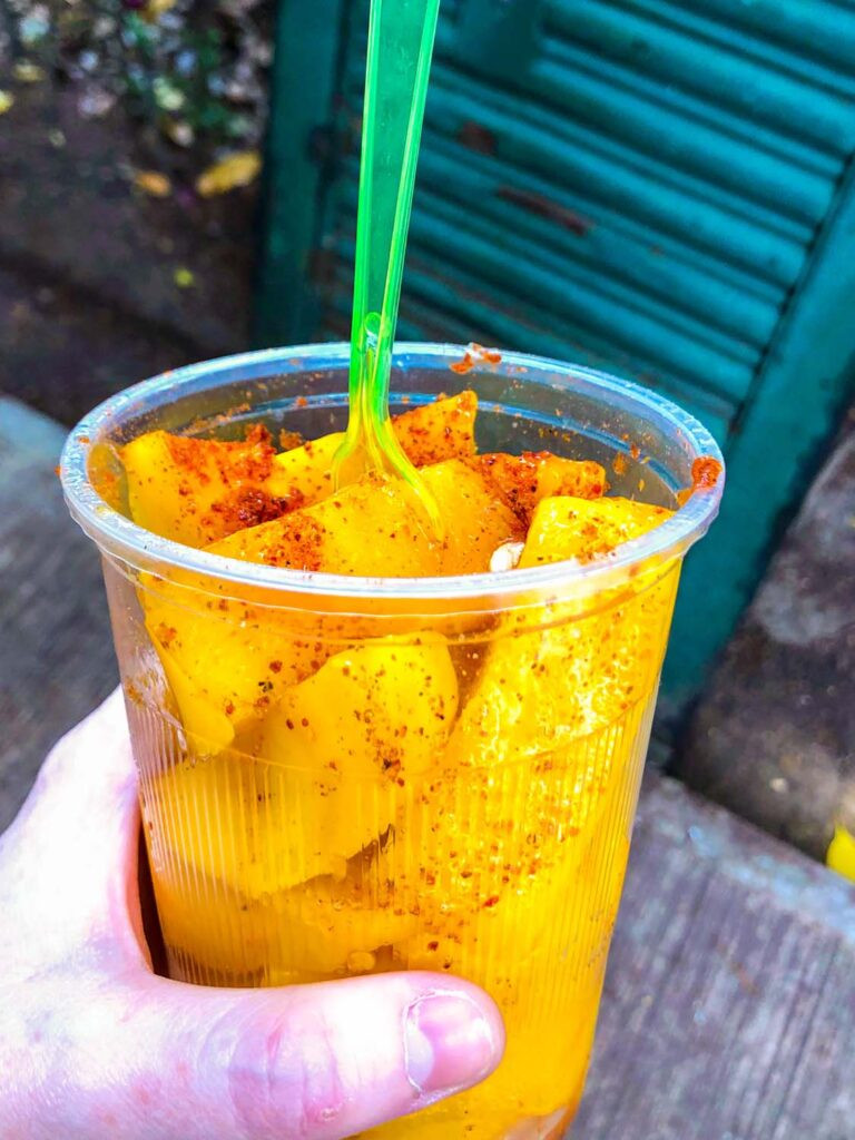 Another close-up image of fresh Mexican street fruit, emphasizing the vibrant colors and the use of chili and chamoy as key flavor enhancers.