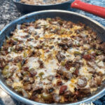 Authentic and delicious Alambre Mexican food featuring seasoned steak, bacon, and vegetables in a skillet.