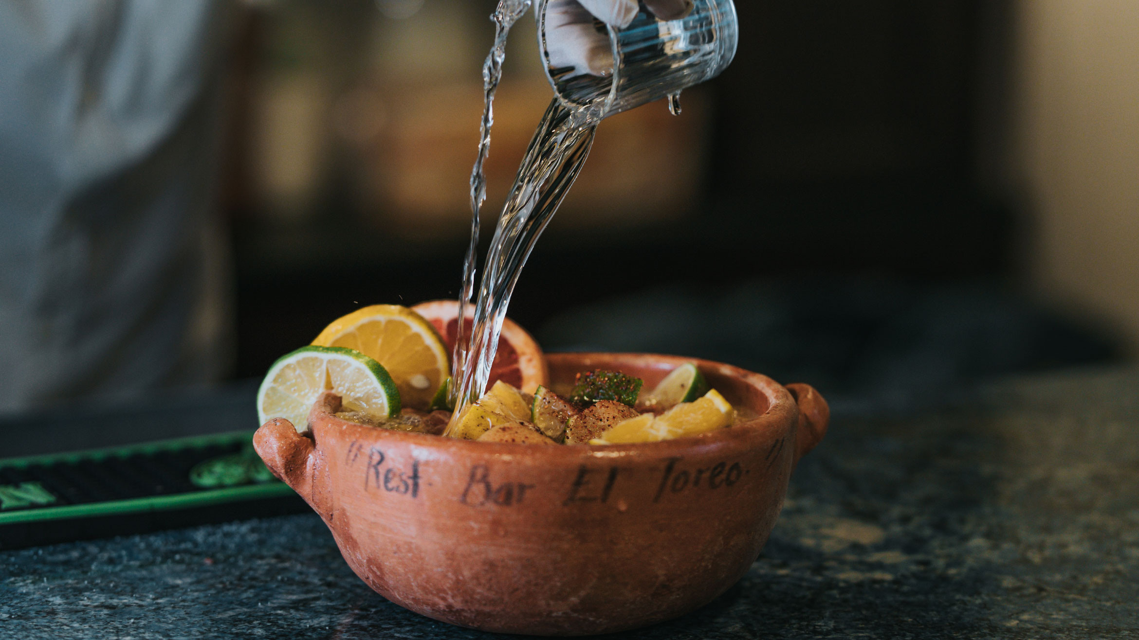 Guadalajara Punch, a large format Mexican cocktail served in a clay cazuela, filled with citrus fruits and garnished with lime wedges.