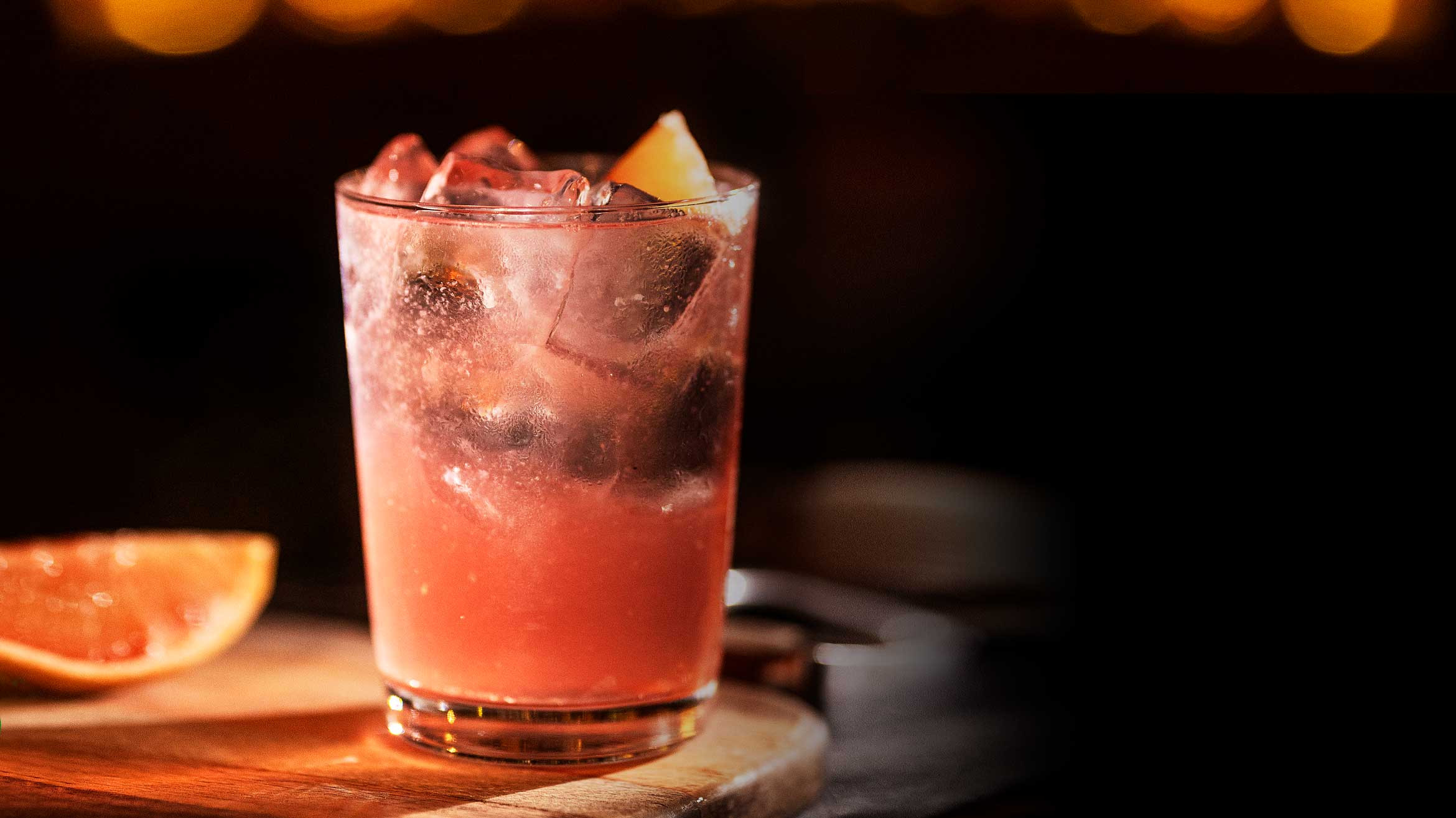 Salmoncito cocktail, a Mexican Gin &amp; Tonic variation with Campari and grapefruit, garnished with a grapefruit wedge resembling a salmon.