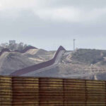 The US-Mexico border wall at Tijuana, separating it from San Diego County, symbolizing the gateway to surfing adventures in Baja.