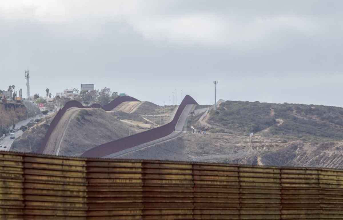 The US-Mexico border wall at Tijuana, separating it from San Diego County, symbolizing the gateway to surfing adventures in Baja.