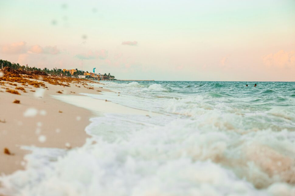 Turquoise waves of a Playa del Carmen beach at sunset, highlighting the town's relaxed atmosphere and safe tourist zones with all-inclusive resorts