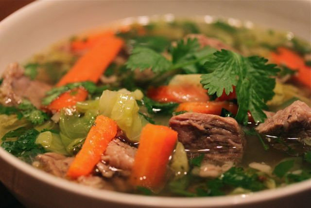 Hearty Caldo de Res served in a bowl with cilantro and lime garnish