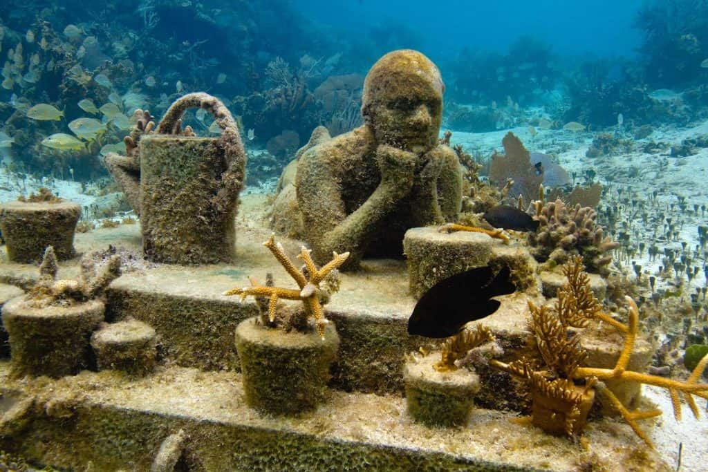 Statue of a person at a table at the Cancun Underwater Museum