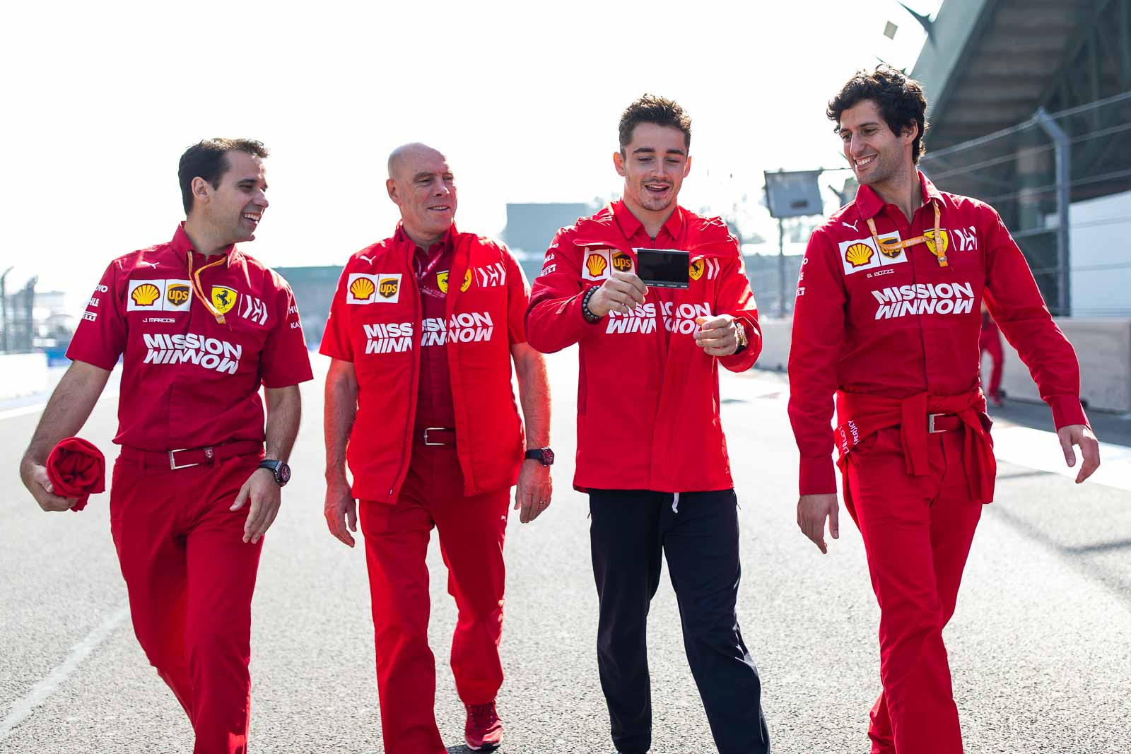 Close-up of Charles Leclerc smiling and holding a polaroid in the Formula 1 paddock during the Mexican Grand Prix