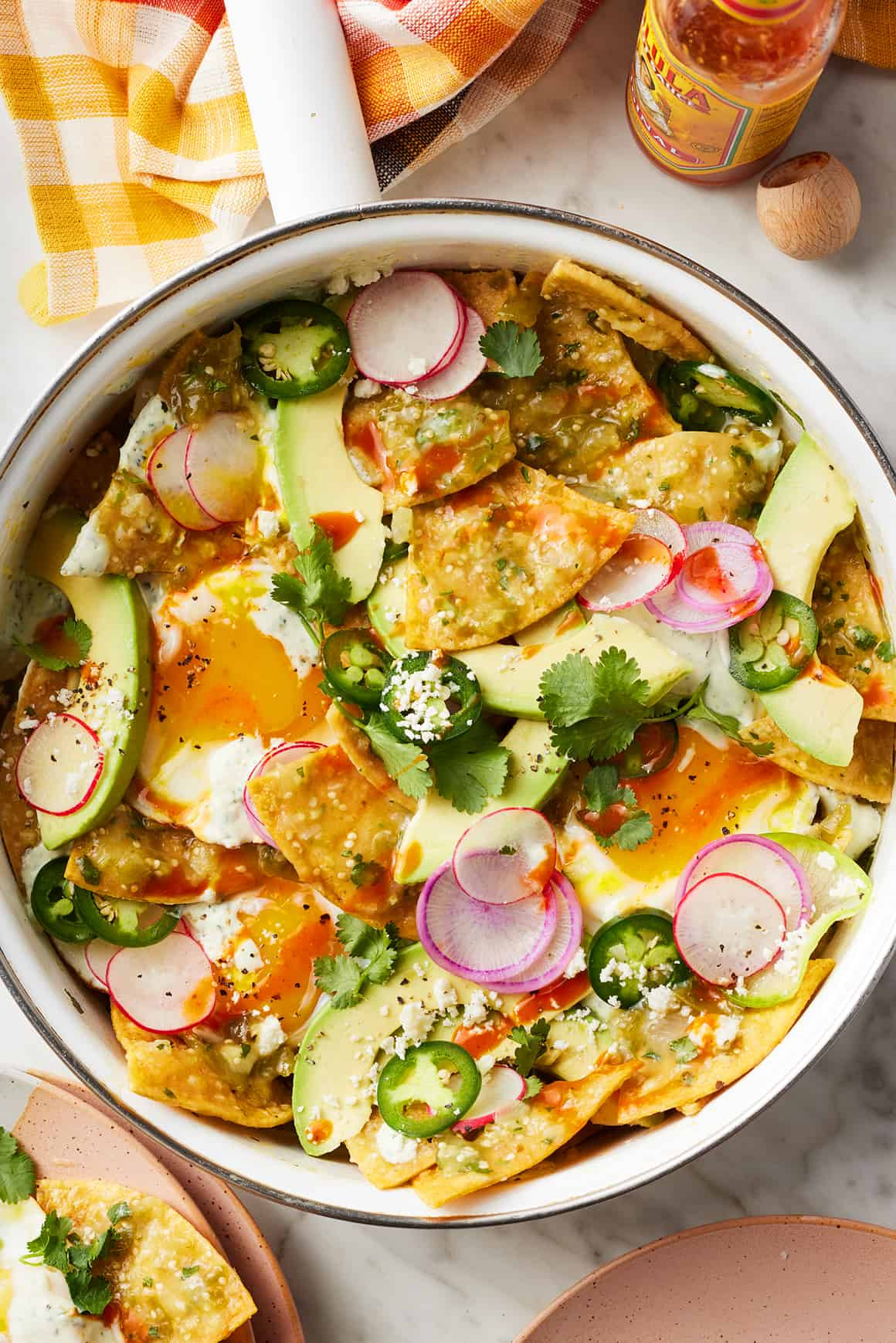 Serving of chilaquiles with fried eggs, crema, and fresh toppings.