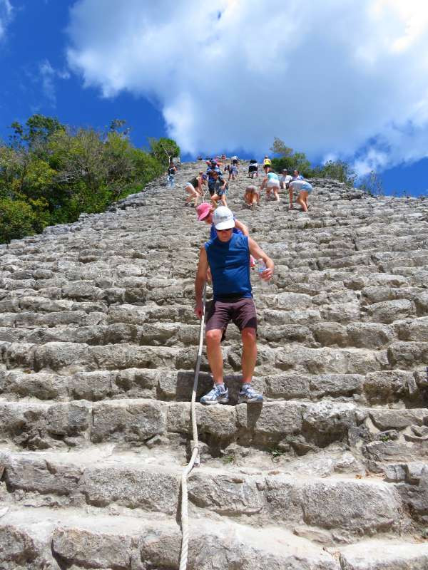 Visitors climbing Nohoch Mul pyramid at Coba ruins, Yucatan, Mexico, experiencing ancient Mayan site and jungle views