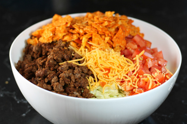 A serving spoon scooping out a portion of Doritos Taco Salad, showing the mix of ingredients and textures in the salad.