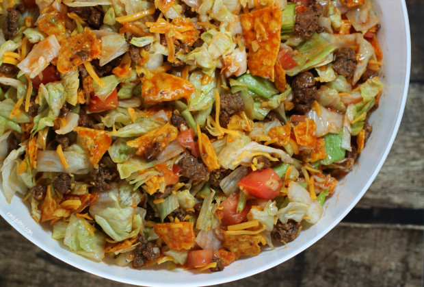 Overhead view of Doritos Taco Salad in a white bowl, highlighting the vibrant colors of the ingredients and the crunchy Doritos on top.