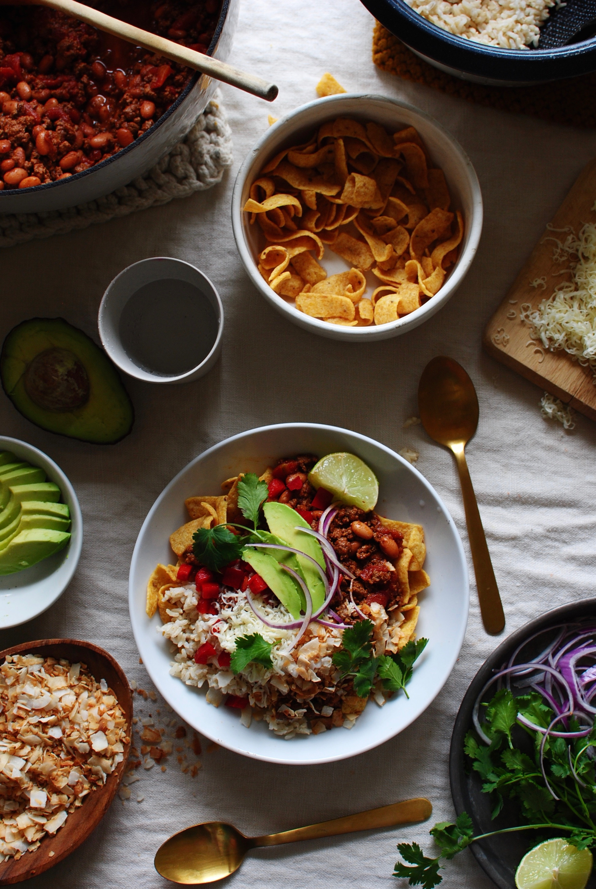 Layering Fritos, rice, chili, and toppings in a Mexican Fiesta Bowl.