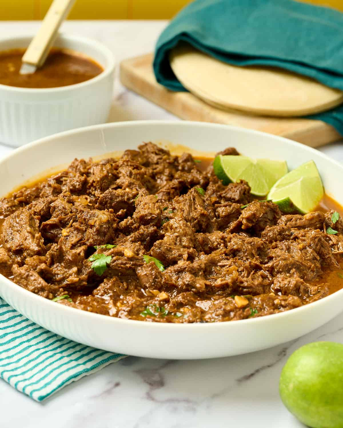 Dutch oven barbacoa in a serving bowl, topped with parsley.
