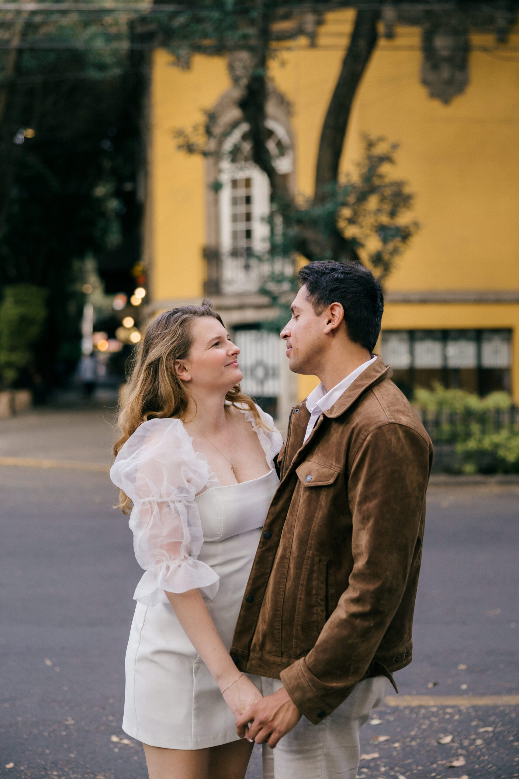 Colorful building mexico pictures: A beautiful couple poses against a vibrant yellow building in Mexico City, showcasing the city's rich colors