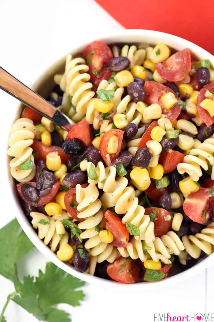 Aerial view of Mexican Pasta Salad in a bowl with a serving spoon, highlighting the fresh lime vinaigrette dressing.