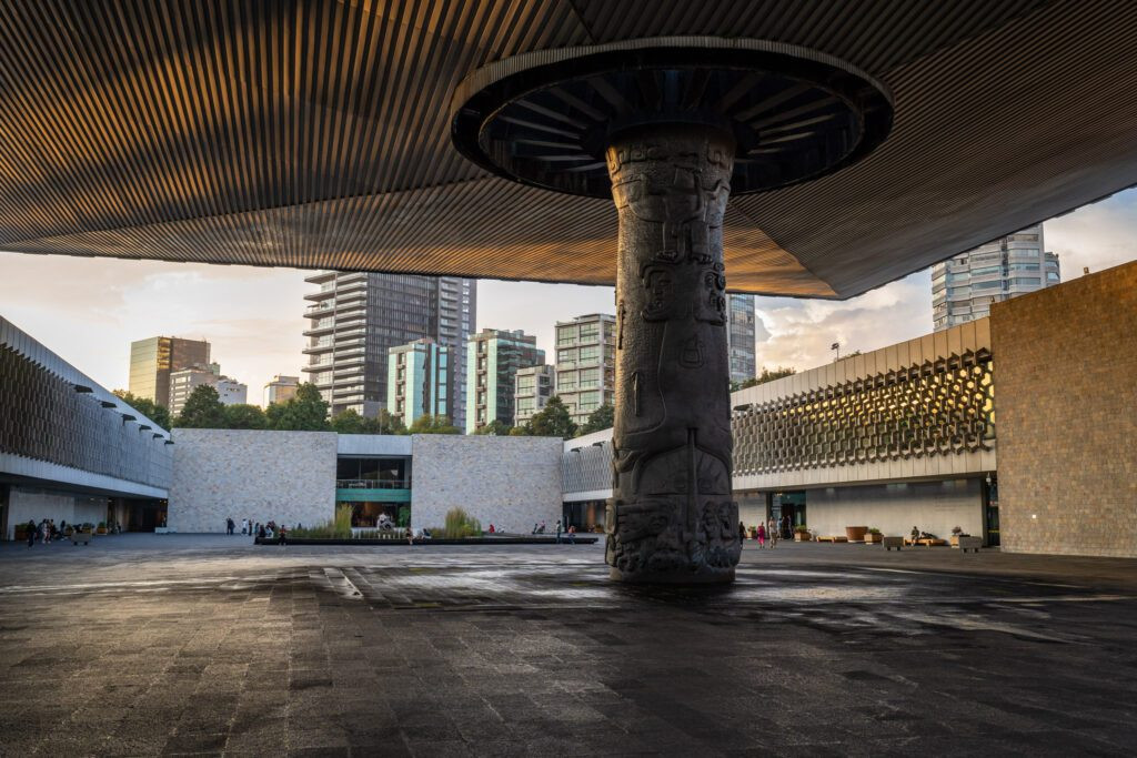 A serene fountain in the courtyard of the Anthropology Museum at golden hour, reflecting the surrounding architecture.