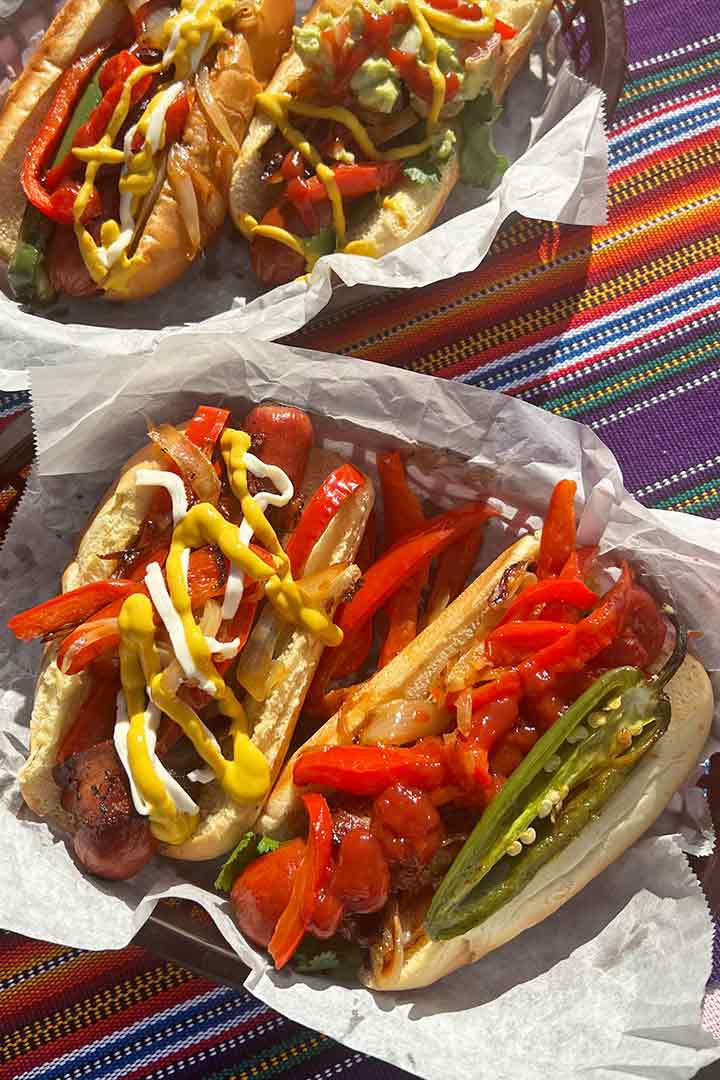 Four fully assembled and delicious Mexican hot dogs, ready to be enjoyed, showcasing various toppings and condiments.
