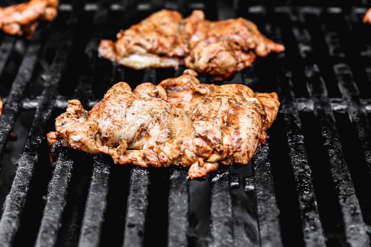 Chicken thighs grilling on a barbecue, sizzling and charring for homemade Mexican street tacos.