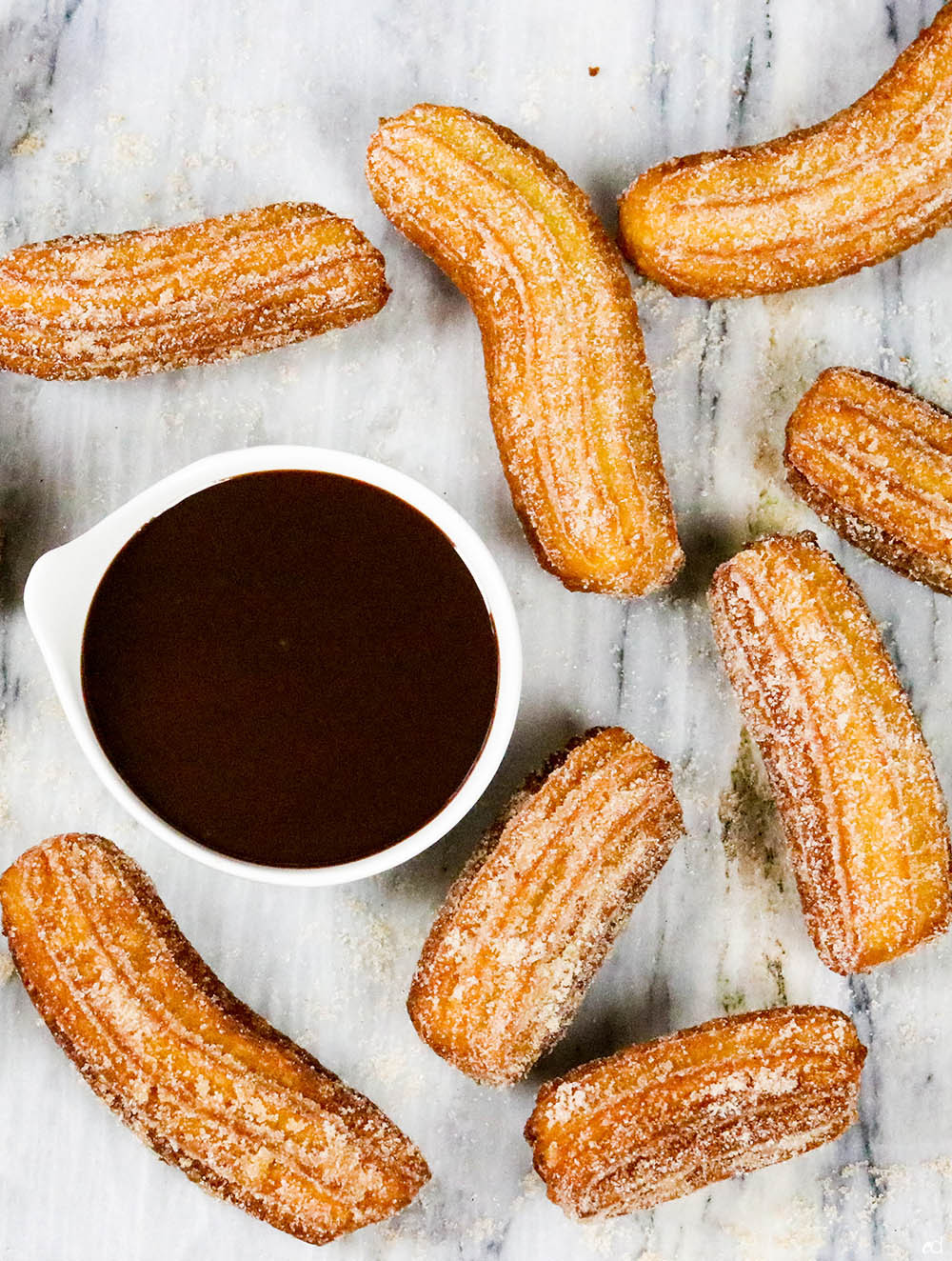Group of freshly fried Mexican churros arranged on a wooden board, ready to be served with chocolate dipping sauce, highlighting their appealing presentation.