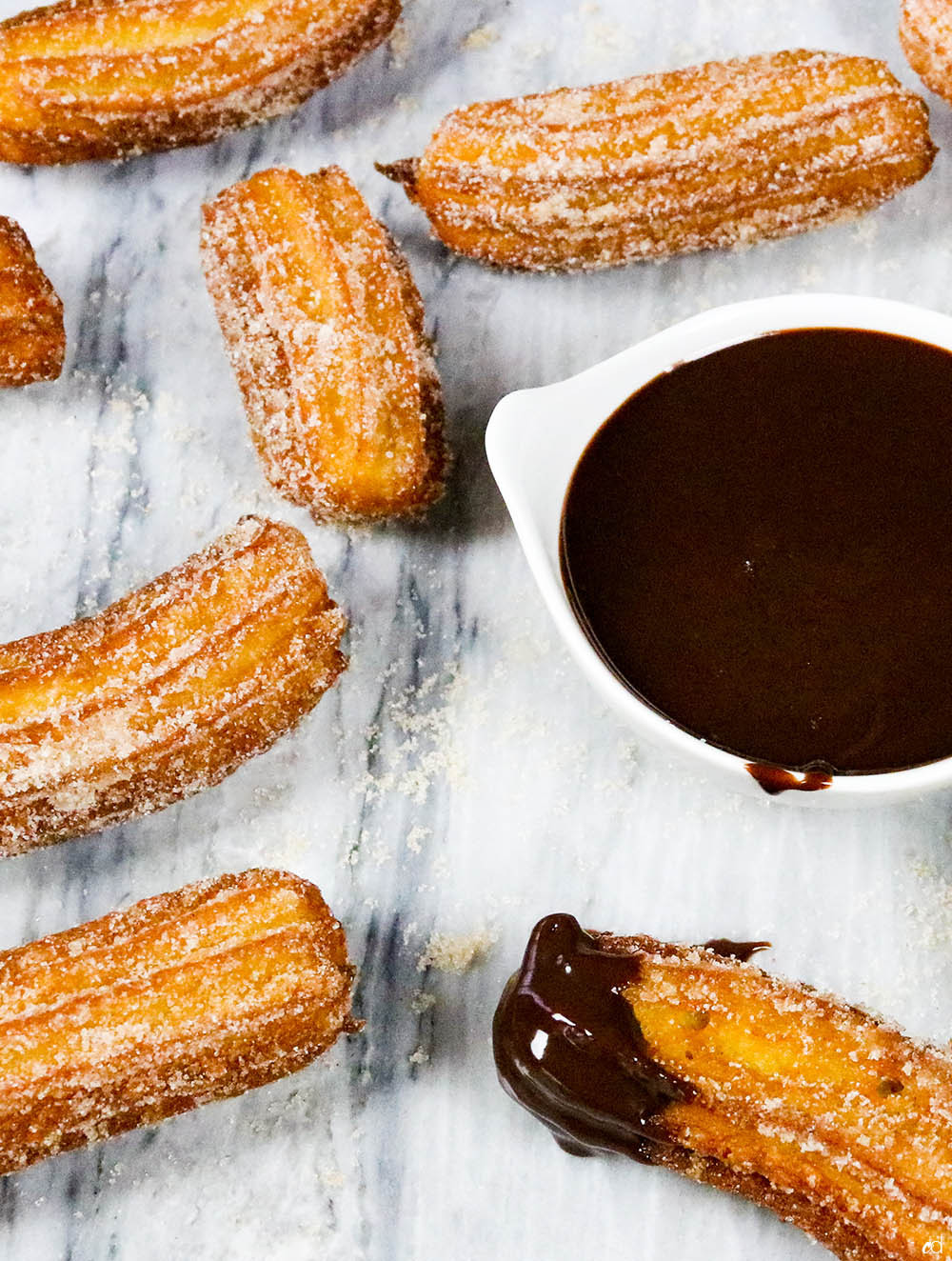 Detailed shot of a single Mexican churro dipped in rich chocolate ganache, emphasizing the contrast between the crispy churro and smooth sauce.
