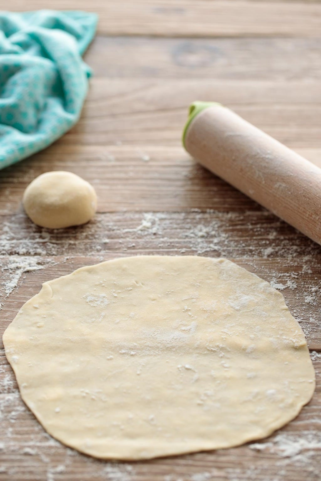 Image showing the process of rolling out a homemade flour tortilla on a lightly floured surface.