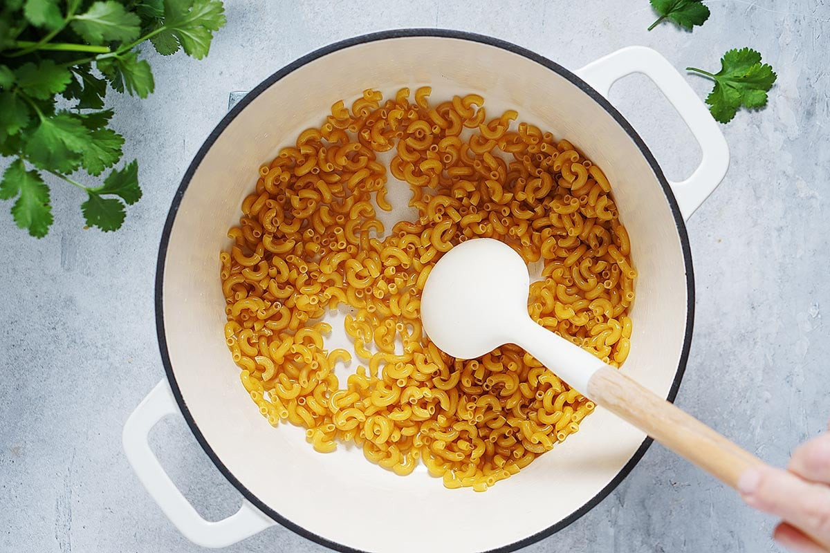 Sautéing pasta in oil in a white pot for mexican sopa recipe.