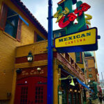 alt text: The exterior of Su Casa Mexican Restaurant at night, showing the neon cactus sign and clay-tile roof.