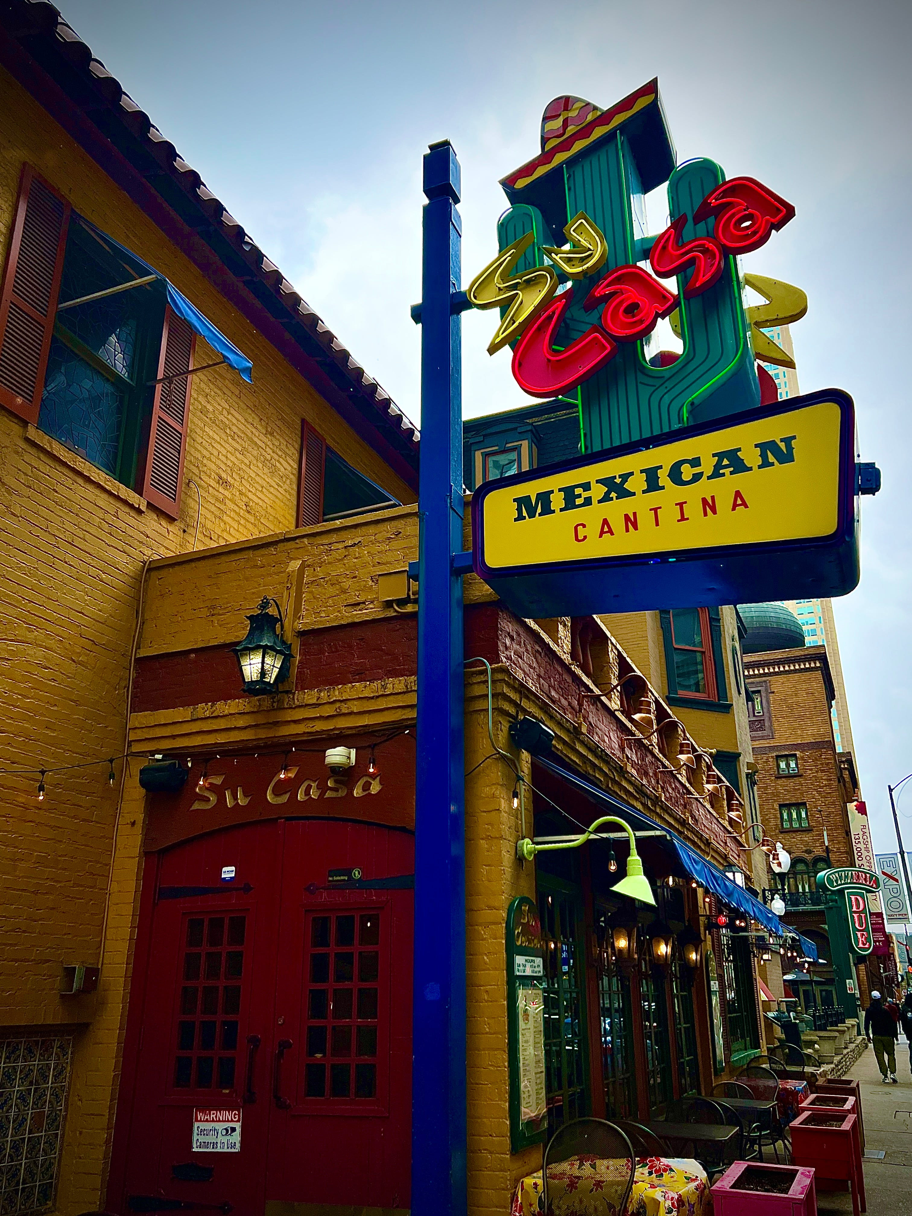 alt text: The exterior of Su Casa Mexican Restaurant at night, showing the neon cactus sign and clay-tile roof.