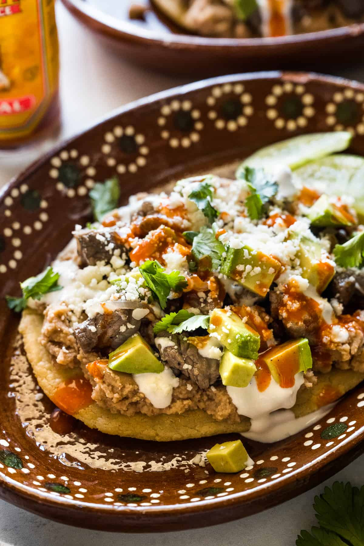 Close-up of a Huarache topped with fresh ingredients like avocado and cheese, showcasing its appetizing appearance.