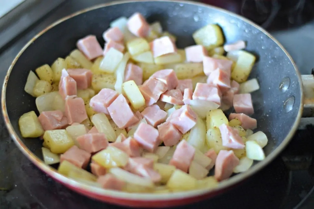 Sautéing potatoes, onions, and ham for Huevos Rancheros, the first step in creating this flavorful Mexican breakfast dish.