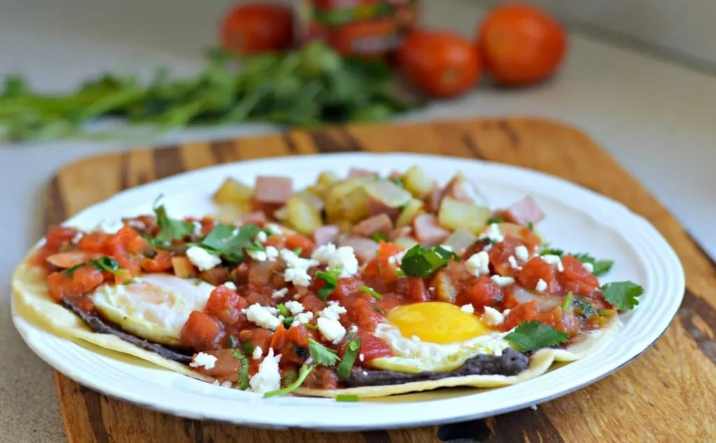 Serving suggestion for Huevos Rancheros, highlighting the potato, onion, and ham mix alongside the egg and tortilla for a complete Mexican breakfast.