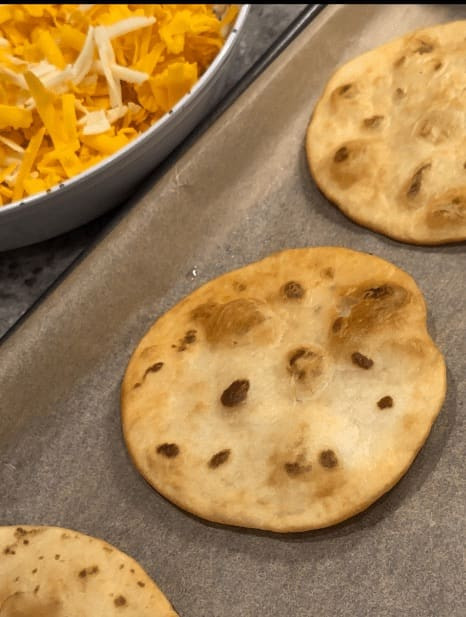 Fried tortillas arranged on a baking sheet lined with parchment paper, ready for layering to make Taco Bell Mexican Pizza.