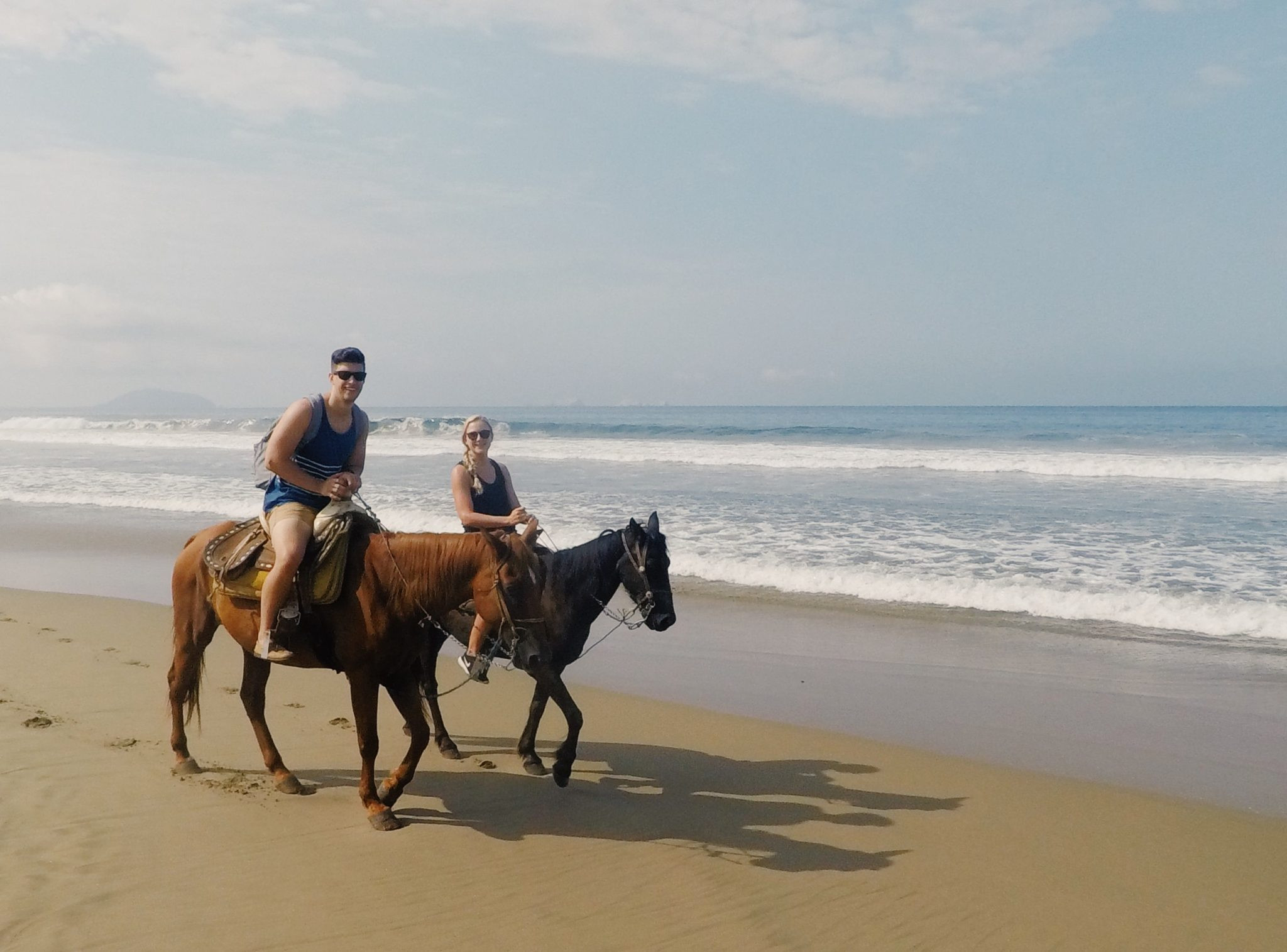 Couple horseback riding on the beach in Zihuatanejo, Mexico