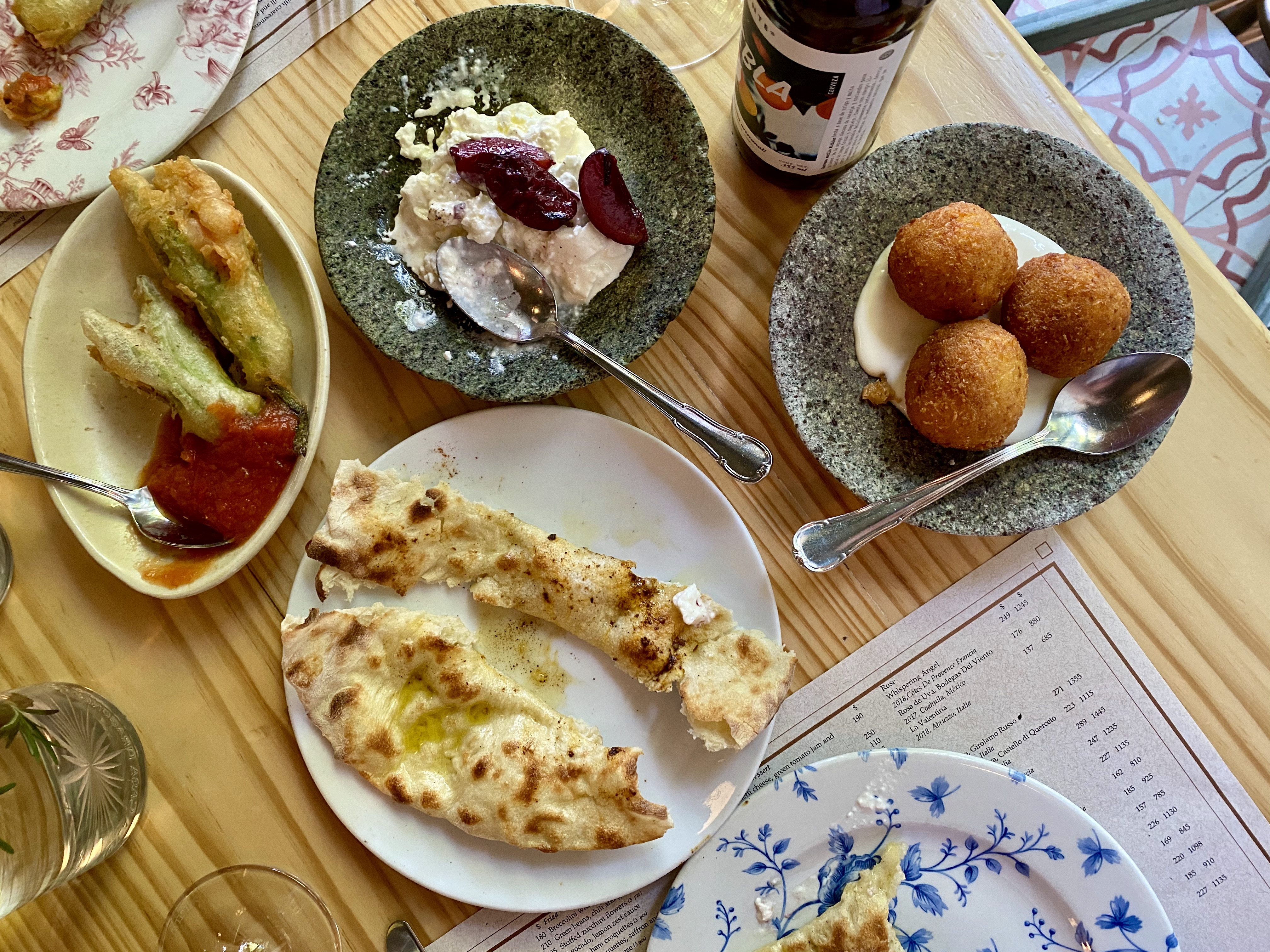 Close-up of a plate with burrata, plums, and pita bread at Lardo restaurant.