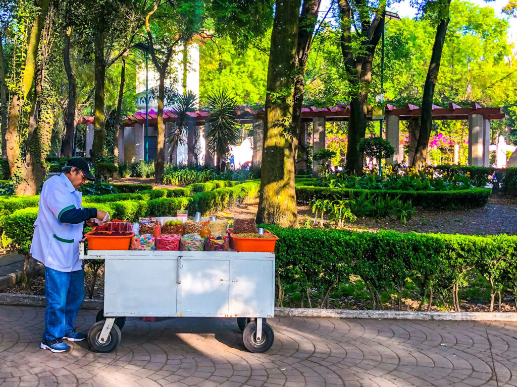 A vibrant Mexican street food snack cart overflowing with colorful candies, nuts, and other treats in Parque Mexico, La Condesa.