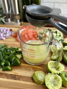 Squeezing fresh lime juice into a measuring cup, showcasing the process of extracting citrus juice for ceviche.