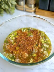 Adding Tajin seasoning to the marinated shrimp ceviche, highlighting the final seasoning step.