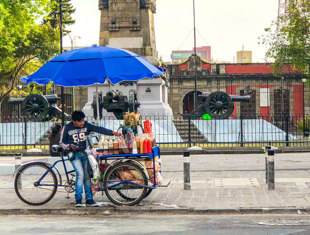 A street food vendor in Mexico preparing fresh fruit with chili and lime, a classic Mexican street food snack.